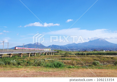 The 381-series limited express Yakumo runs over the long railway bridge of the Hino River with Mt. Daisen in the background. 109213354