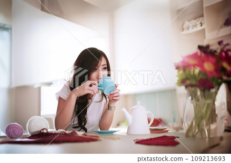 Happy single Asian woman doing knitting hobby alone in the house 109213693