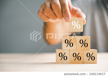 Illustrating the concept of interest rate and financial ranking. Businessman's hand placing a wooden cube block with a percentage symbol icon, representing the dynamic nature of rates. 109214657