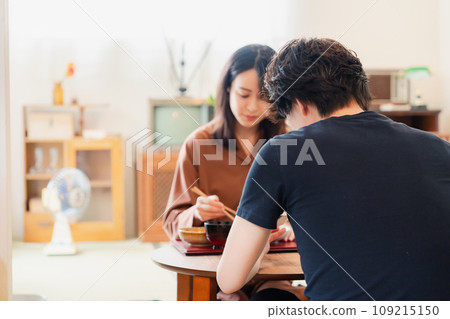 A young couple eating dinner at a table with a retro atmosphere reminiscent of a drama. 109215150