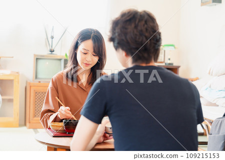 A young couple eating dinner at a table with a retro atmosphere reminiscent of a drama. 109215153