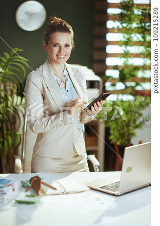 smiling woman employee in green office using smartphone 109215289