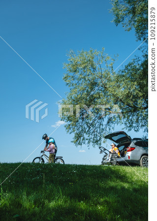 happy family outdoors father teaching daughter yo bicycle mother sitting in car trunk happy family outdoors father teaching daughter yo bicycle mother sitting in car trunk 109215879