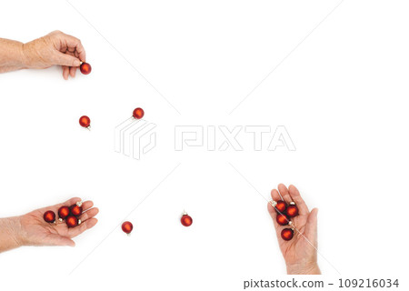 Happy greeting card. Elderly wrinkled female hands hold beautiful red Christmas toys in palms on white background. Copy space. Top View 109216034