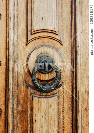 Brown wooden door with brass knocker. Old elegant metal door handle 109216175