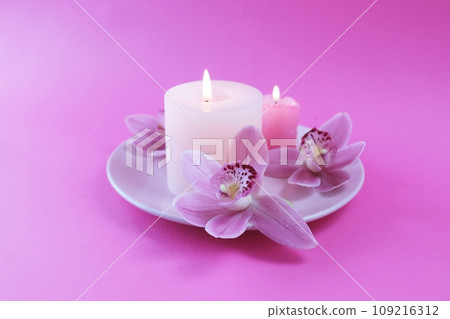 Fresh pink orchid flowers, burning candles, sea salt, on a bright pink background, spa concept, relaxation atmosphere, body care  109216312