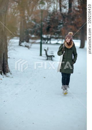 pensive modern woman outdoors in city park in winter 109216410