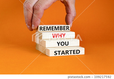 Remember why you started symbol. Concept word Remember why you started on wooden block. Beautiful orange table background. Businessman hand. Business remember why you started concept. Copy space. 109217592