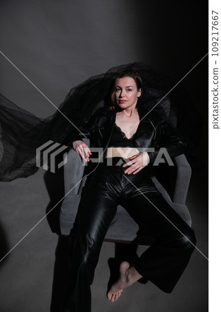 Woman in black clothes in an armchair in a dark room 109217667