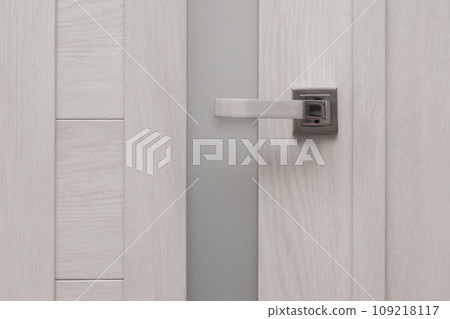 Silver metal color door handle made of white wood home exit house interior decoration, close-up 109218117