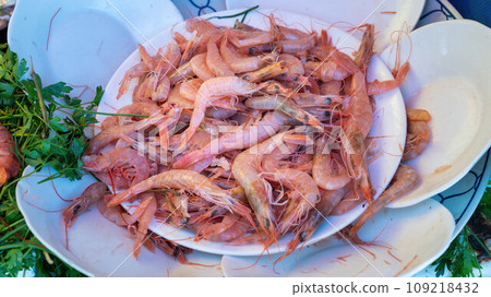 Dish of shrimp at the Essaouira fish market. Fishermen skillfully clean and prepare the catch, offering the coastal traditions that define Essaouira's culinary culture. 109218432