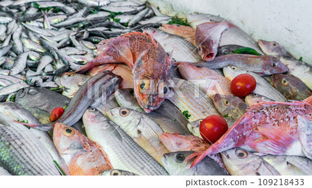 Stall at the Essaouira fish market with a variety of fresh seafood. Fishermen skillfully clean and prepare the catch, offering the coastal traditions that define Essaouira's culinary culture. Stall at the Essaouira fish market with a variety of fresh seafood. Fishermen skillfully clean and prepare the catch, offering the coastal traditions that define Essaouira's culinary culture. 109218433