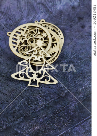 Flat wooden toy in the shape of a Christmas tree lies on a set of other wooden toys on a blue background, vertical photo Flat wooden toy in the shape of a Christmas tree lies on a set of other wooden toys on a blue background, vertical photo 109218482