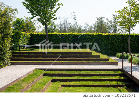 Seating for relaxing in a landscaped park. Minimalist landscape design with green grass steps 109218571