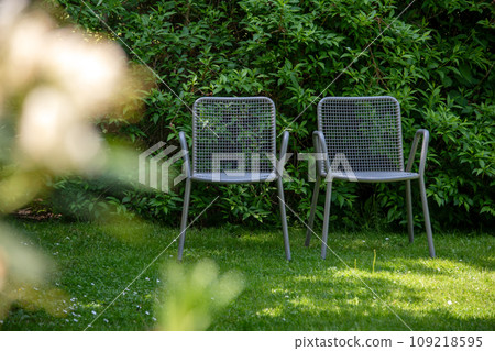 Metal chairs in spring garden. Metal garden furniture for picnics and birdwatching Metal chairs in spring garden. Metal garden furniture for picnics and birdwatching 109218595