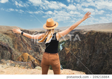 A woman tourist delighted with upper part of the Charyn River, which flows through the Charyn Canyon in Kazakhstan in the Almaty region 109218864