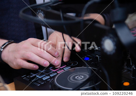 A DJ in a nightclub at the control panel adjusts the music. Music is playing, creating an atmosphere. High quality photo A DJ in a nightclub at the control panel adjusts the music. Music is playing, creating an atmosphere. High quality photo 109220246