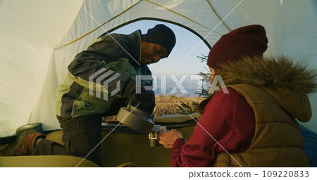 Tourist couple warm up at windy weather on mountain 109220833