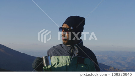 Tourist drinks cup of tea on top of mountain hill Tourist drinks cup of tea on top of mountain hill 109220940