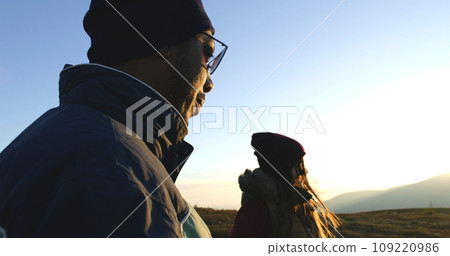 Young couple of hikers rests and enjoys of view on top of hill Young couple of hikers rests and enjoys of view on top of hill 109220986