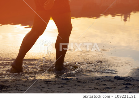 A man is running along the coast, training, legs and water closeup. 109221151
