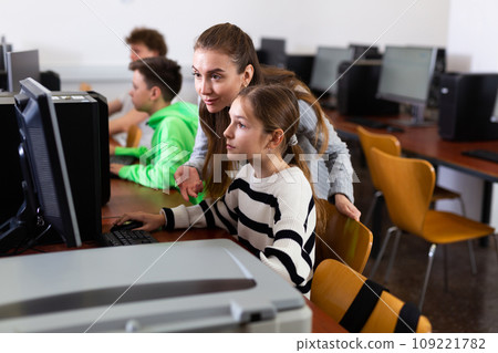 Female teacher helping teen schoolgirl studying in computer lab Female teacher helping teen schoolgirl studying in computer lab 109221782