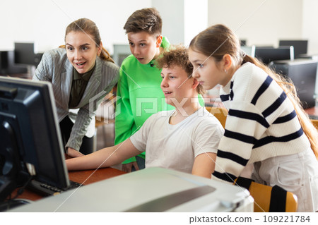 Female teacher and teen students looking at monitor screen during lesson Female teacher and teen students looking at monitor screen during lesson 109221784