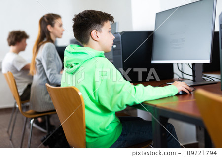 Schoolboy using computer at lesson, teacher teaching pupils in class room Schoolboy using computer at lesson, teacher teaching pupils in class room 109221794