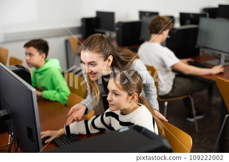 Female teacher talking to focused teen girl student in computer class 109222002