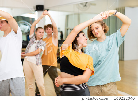Group of teenage boys and girls training slow foxtrot movements in dance studio 109222040