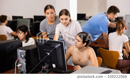 Portrait of young girls using pc and discussing while studying in computer class Portrait of young girls using pc and discussing while studying in computer class 109222088