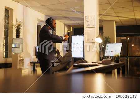 Positive worker dancing and having fun in startup office, enjoying listening music during work break. African american executive manager doing dance moves after finishing company investment strategy Positive worker dancing and having fun in startup office, enjoying listening music during work break. African american executive manager doing dance moves after finishing company investment strategy 109222138