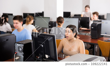Focused teenager students sitting at desk in computer room with pc, preparing for exam. Focus on young girl 109222141