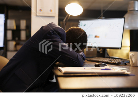 Workaholic businessman slepping desk in startup office, after checking marketing statistics on computer. Exhausted tired entrepreneur working overtime at company strategy plan. Business concept Workaholic businessman slepping desk in startup office, after checking marketing statistics on computer. Exhausted tired entrepreneur working overtime at company strategy plan. Business concept 109222200