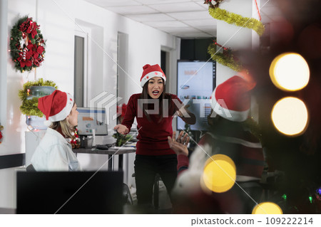 Manager angry at employees, frustrated by weak company performance after checking year end analytics during Christmas season. Management executive yelling at staff members in festive decorated office 109222214