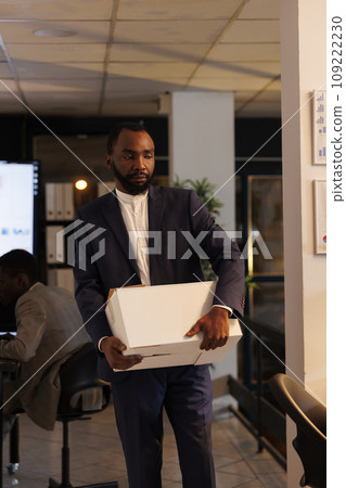 Stressed sad businessman getting fired from corporate job ready to leave office late at night. Upset executive manager packing personal belongings in cardboard box. Business concept 109222230