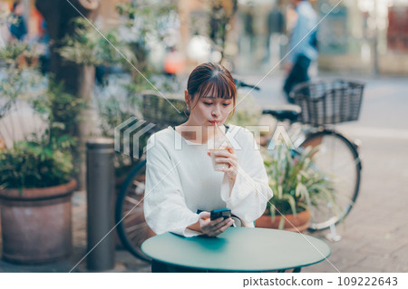 一位年輕女子在咖啡館操作智慧型手機 109222643