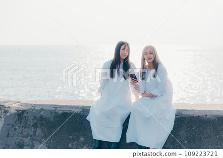 照片：兩名年輕女性在海灘上看智慧型手機 109223721