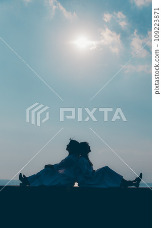Silhouette photo of two young women standing by the seaside Silhouette photo of two young women standing by the seaside 109223871