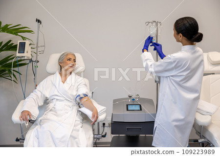 Woman receiving intravenous vitamin therapy attached to vitamin IV infusion drip in beauty salon. Woman receiving intravenous vitamin therapy attached to vitamin IV infusion drip in beauty salon. 109223989