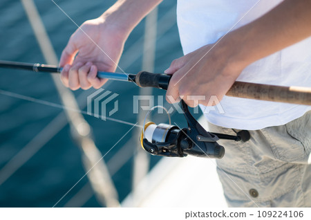 Young guy in white with a fishing rod on the yacht 109224106