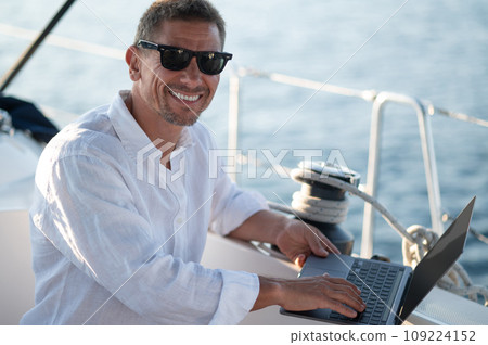 Successful mature man with a laptop working on a yacht 109224152