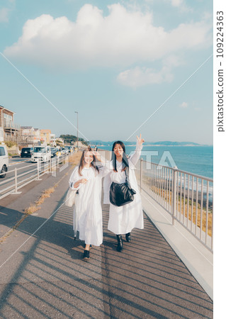 Two young women walking by the seaside 109224363