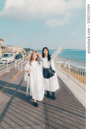 Two young women walking by the seaside 109224364
