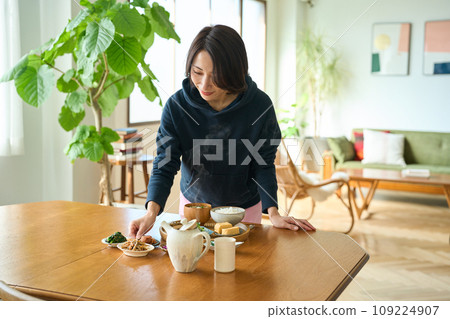 假日早晨，一名婦女在餐桌上提供食物 109224907