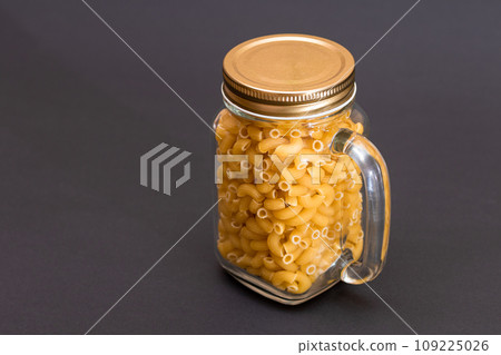 Uncooked Chifferi Rigati Pasta in Glass Jar on Black Background 109225026