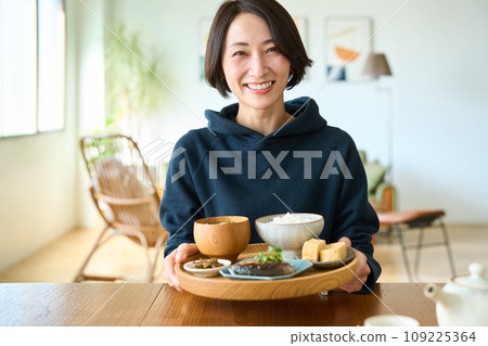 A woman holding a tray with breakfast in her hand 109225364