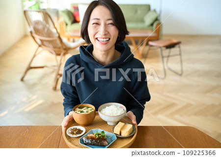 一個女人手裡拿著一個托盤，手裡拿著早餐 109225366