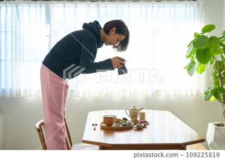 A woman photographing food with a camera 109225819