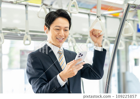 一名中年商人在通勤列車上看著智慧型手機。照片由京王電鐵株式會社提供。 一名中年商人在通勤列車上看著智慧型手機。照片由京王電鐵株式會社提供。 109225857